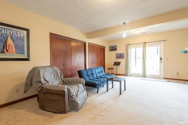 carpeted living room featuring a textured ceiling and baseboards