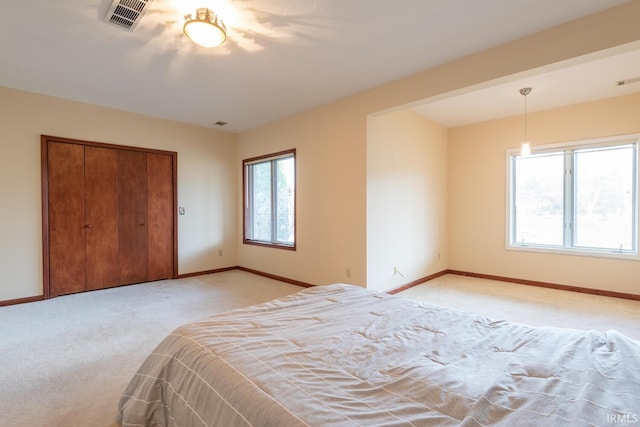 unfurnished bedroom featuring baseboards, visible vents, a closet, and light carpet