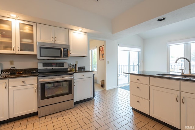 kitchen with white cabinets, stainless steel appliances, glass insert cabinets, and a sink