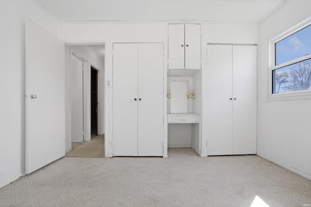 unfurnished bedroom featuring light colored carpet and two closets