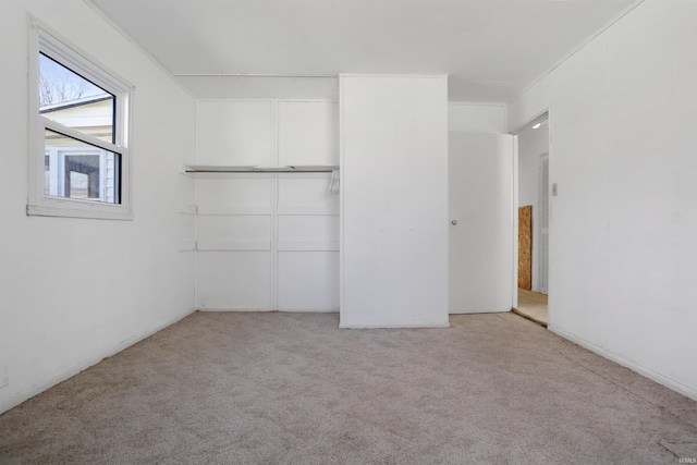 unfurnished bedroom with crown molding, light colored carpet, and a closet