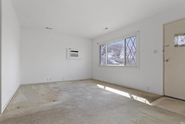 unfurnished room with an AC wall unit, visible vents, and carpet floors