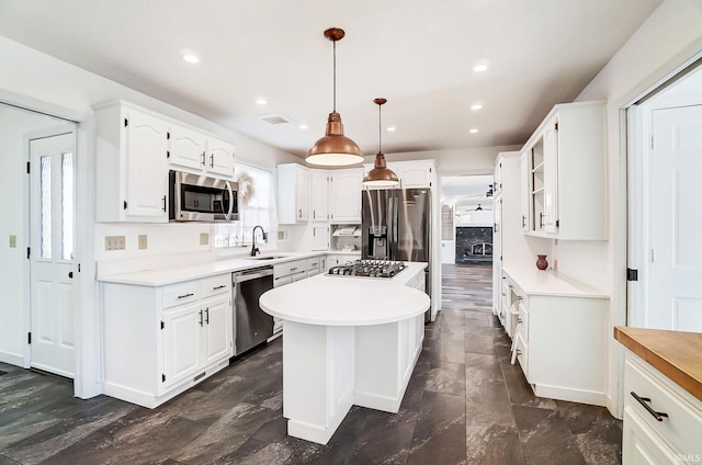 kitchen with a sink, a center island, appliances with stainless steel finishes, white cabinets, and light countertops