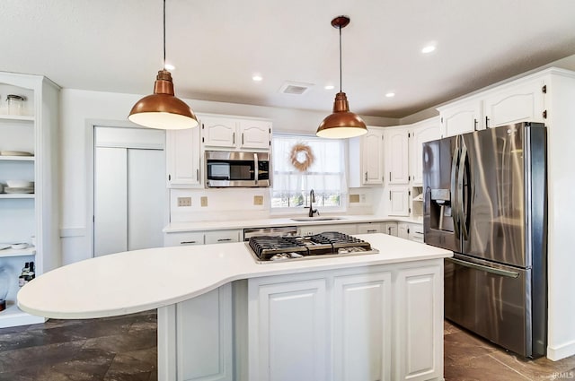 kitchen with a sink, appliances with stainless steel finishes, light countertops, and white cabinetry