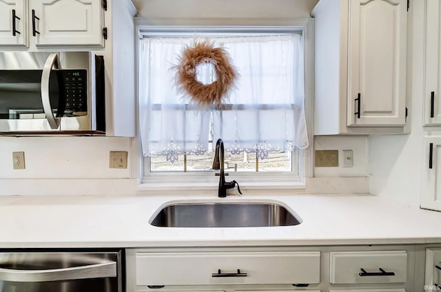 kitchen featuring a sink, stainless steel appliances, white cabinetry, and light countertops