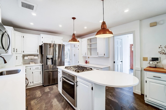 kitchen featuring visible vents, a sink, a kitchen island, white cabinetry, and stainless steel appliances