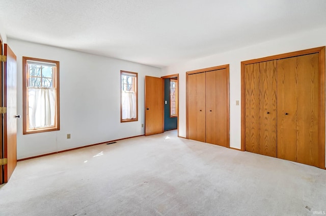 unfurnished bedroom with multiple closets and carpet floors