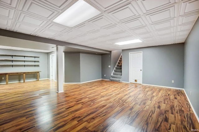 finished basement featuring stairway, an ornate ceiling, baseboards, and wood finished floors