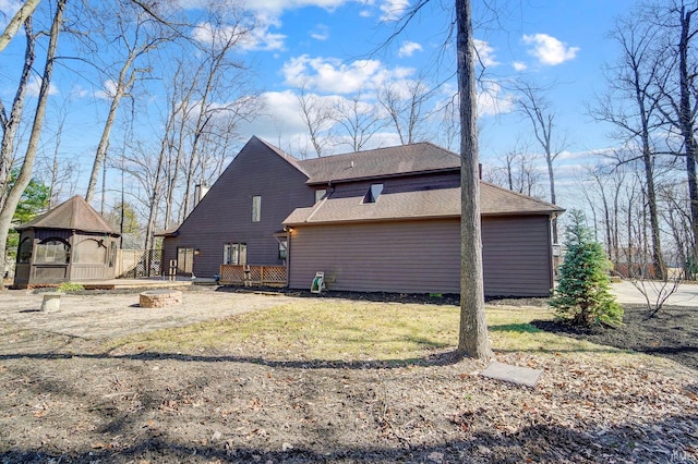 back of property with a gazebo, a yard, and an outdoor fire pit