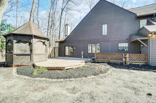 rear view of house featuring a shingled roof and a wooden deck