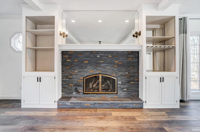 unfurnished living room with a glass covered fireplace, a healthy amount of sunlight, and wood finished floors