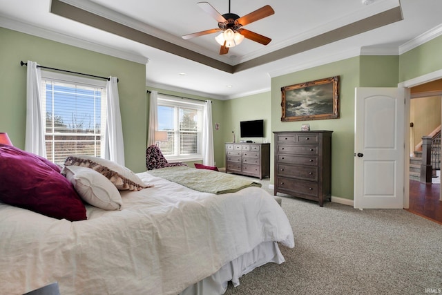 carpeted bedroom featuring ceiling fan, baseboards, a raised ceiling, and ornamental molding