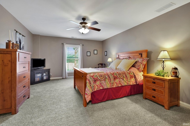 bedroom featuring visible vents, light colored carpet, a ceiling fan, and baseboards