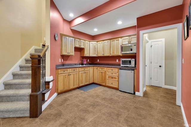 kitchen featuring stainless steel microwave, dark countertops, refrigerator, and light brown cabinets