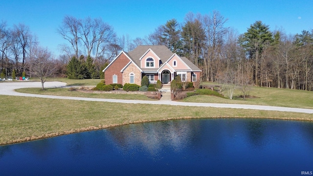 traditional home with a water view, brick siding, and a front lawn