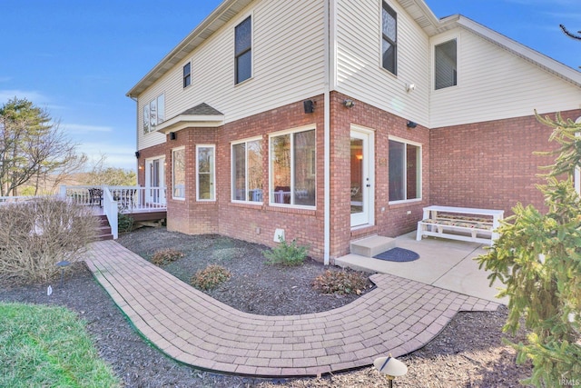 back of property with a patio, crawl space, brick siding, and a wooden deck