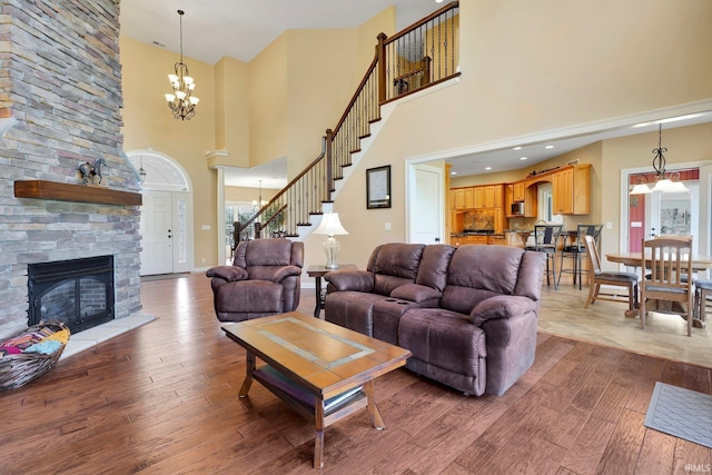 living room featuring baseboards, stairs, a fireplace, hardwood / wood-style flooring, and a notable chandelier