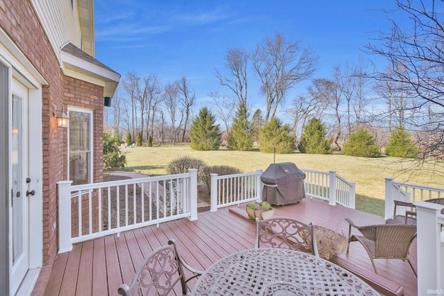 wooden deck with area for grilling, a lawn, and outdoor dining space