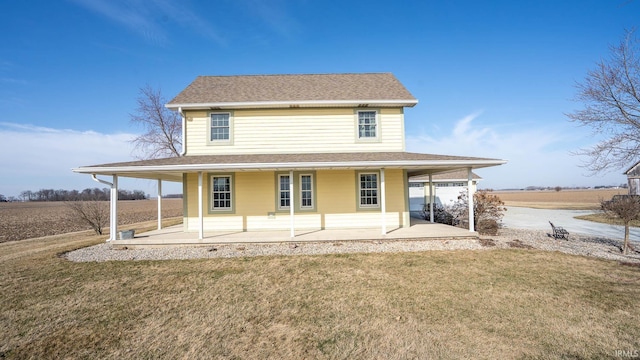 rear view of house with a yard, a patio area, and a shingled roof