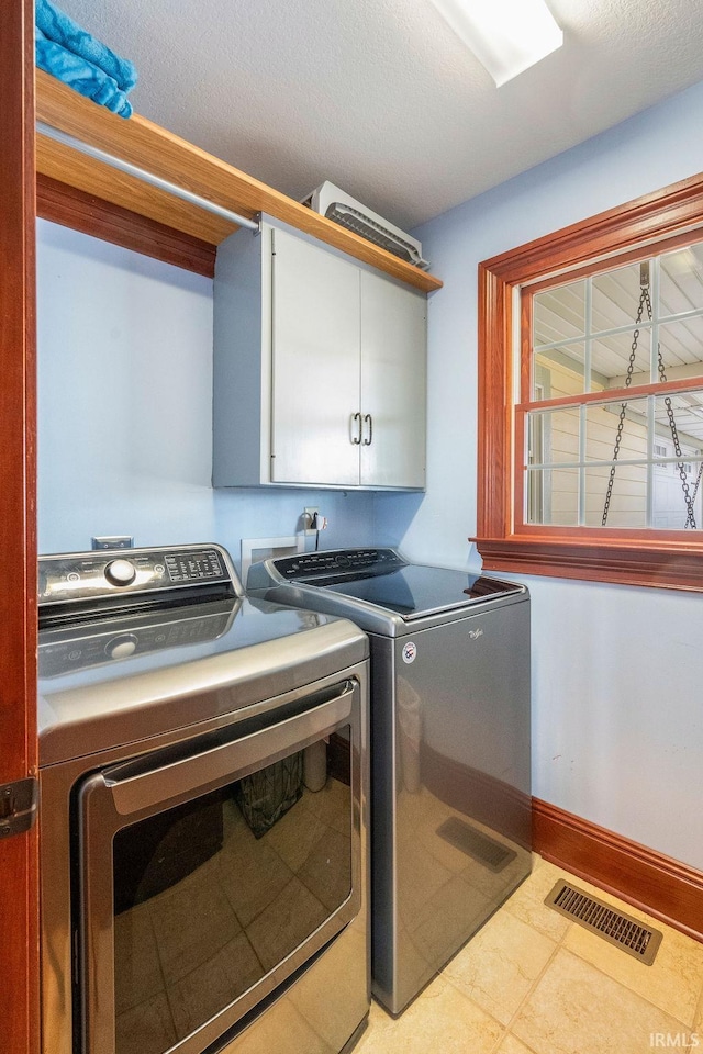 laundry area with washing machine and clothes dryer, visible vents, cabinet space, and baseboards