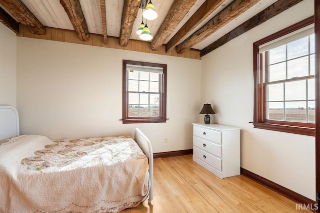 bedroom with beamed ceiling, light wood-style flooring, and baseboards