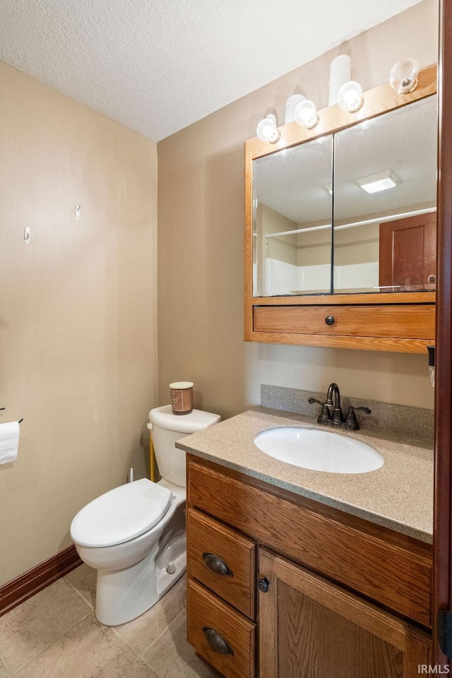 bathroom with vanity, baseboards, tile patterned flooring, a textured ceiling, and toilet