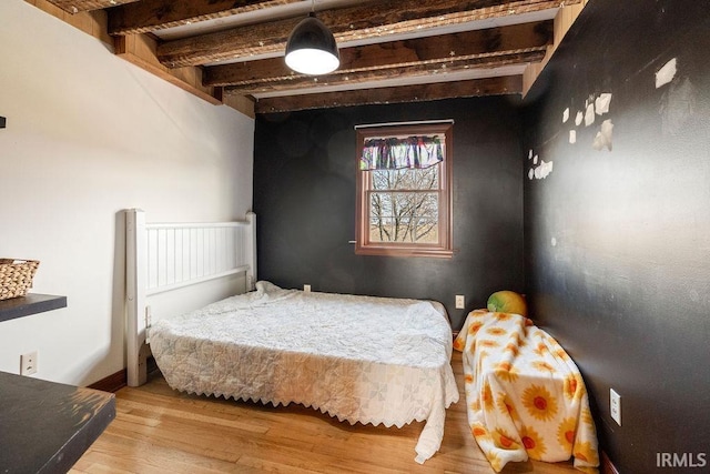 bedroom featuring beamed ceiling and wood finished floors