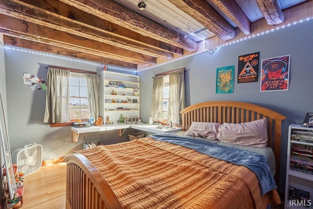 bedroom featuring beam ceiling and wood finished floors