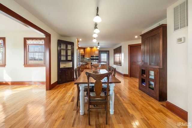 dining space featuring visible vents, baseboards, and light wood finished floors