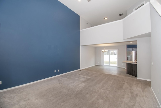 803 Knights Xing, Kendallville, IN 46755 - unfurnished living room featuring visible vents, baseboards, light carpet, an inviting chandelier, and a towering ceiling