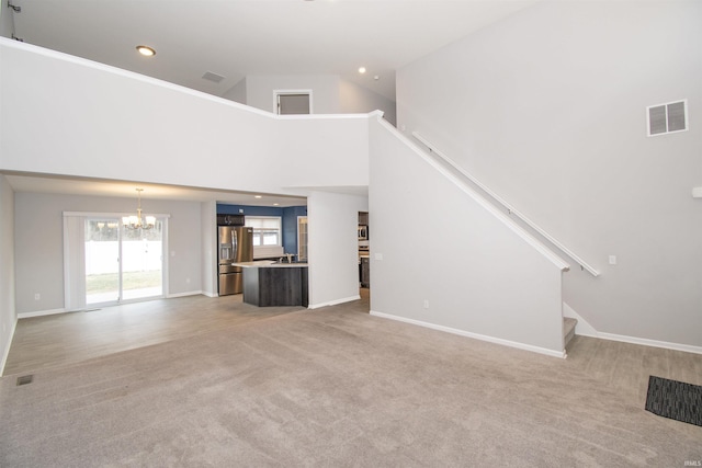 803 Knights Xing, Kendallville, IN 46755 - unfurnished living room with visible vents, light carpet, high vaulted ceiling, and a chandelier