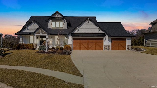 view of front of house featuring stone siding, a lawn, an attached garage, and concrete driveway