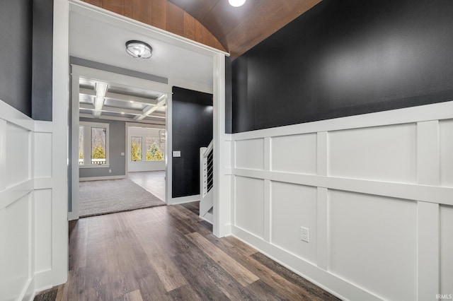 corridor with baseboards, beamed ceiling, wood finished floors, a decorative wall, and coffered ceiling