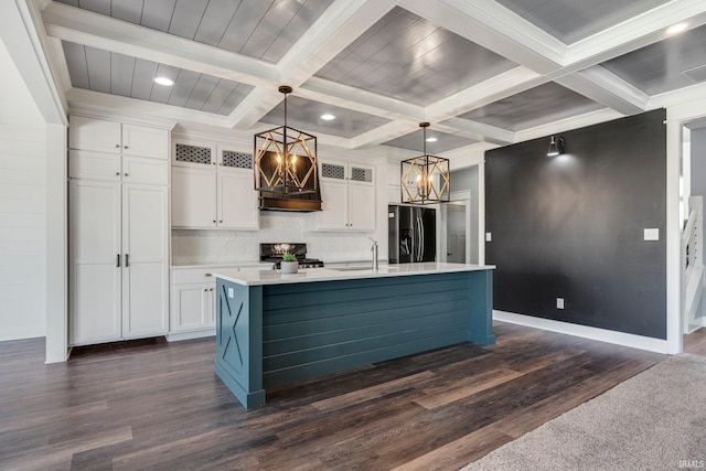 kitchen with a kitchen island with sink, stainless steel refrigerator with ice dispenser, stove, white cabinets, and a sink