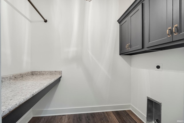 laundry area featuring electric dryer hookup, baseboards, cabinet space, and dark wood-type flooring