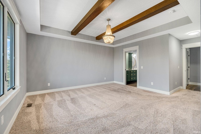 carpeted spare room with visible vents, beamed ceiling, and baseboards