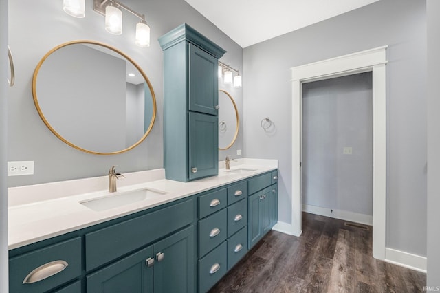 bathroom featuring a sink, baseboards, wood finished floors, and double vanity