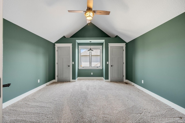 interior space featuring a ceiling fan, carpet, baseboards, and vaulted ceiling