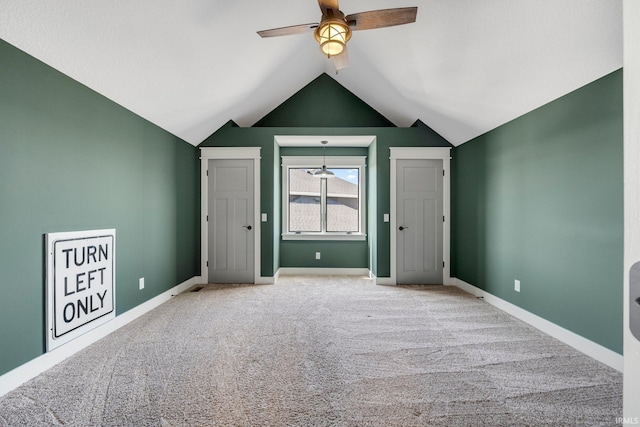 interior space with baseboards, lofted ceiling, a ceiling fan, and carpet floors