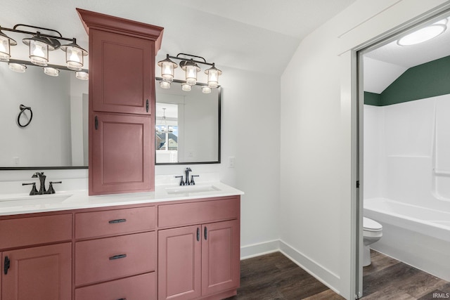 bathroom featuring vaulted ceiling, toilet, wood finished floors, and a sink