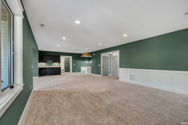 unfurnished living room with recessed lighting, visible vents, light carpet, and baseboards