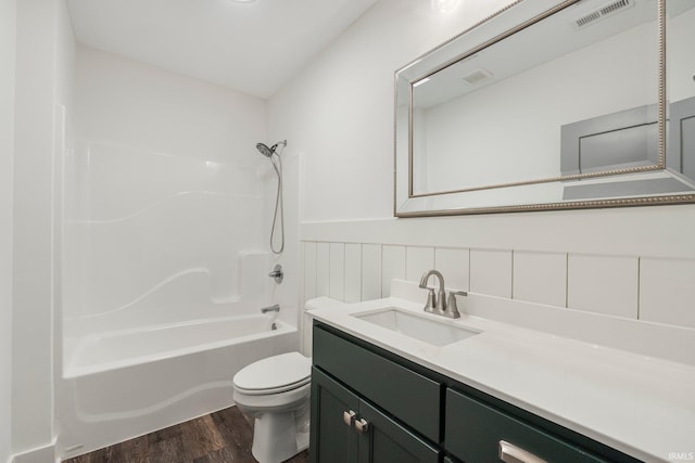 full bathroom with wood finished floors, visible vents, wainscoting, toilet, and shower / bathtub combination