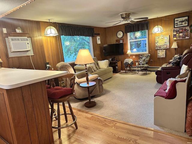 living area with wood walls, light wood-type flooring, light carpet, a wall mounted AC, and a ceiling fan