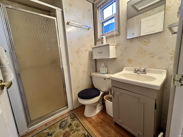 bathroom featuring wallpapered walls, a shower stall, vanity, and wood finished floors