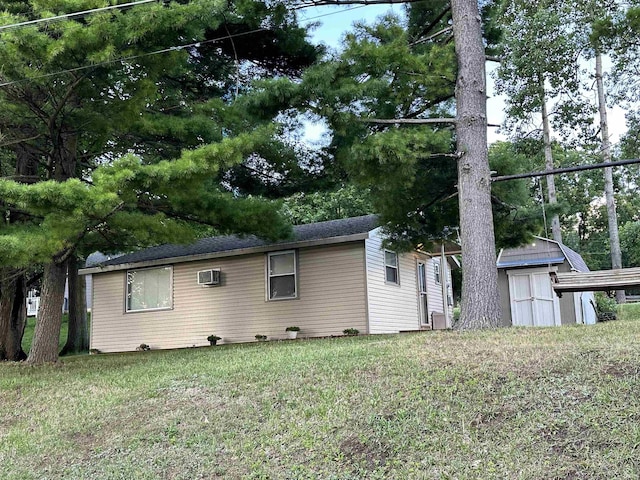 exterior space featuring a wall mounted air conditioner, a storage unit, an outbuilding, and a front lawn