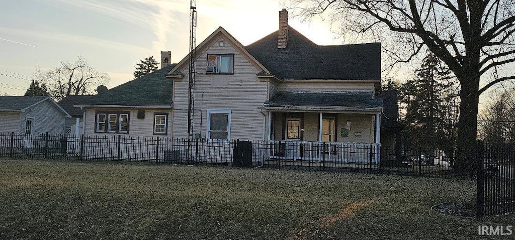 rear view of house featuring a yard, fence, covered porch, and a chimney