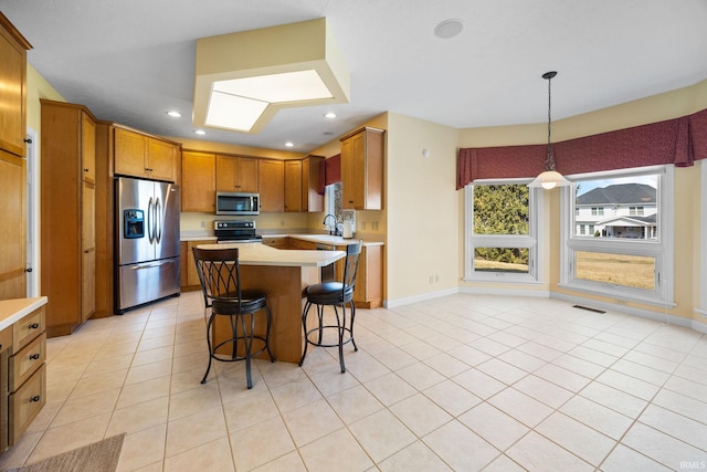 kitchen featuring visible vents, a sink, stainless steel appliances, light countertops, and a kitchen breakfast bar