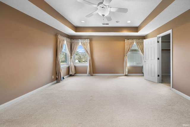 carpeted empty room with a ceiling fan, baseboards, visible vents, recessed lighting, and a raised ceiling