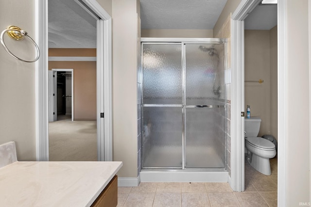 full bath featuring vanity, a stall shower, a textured ceiling, tile patterned floors, and toilet