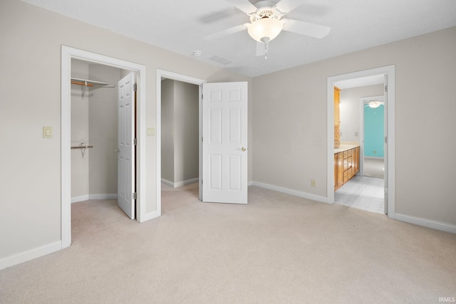 unfurnished bedroom with a walk in closet, baseboards, ceiling fan, light colored carpet, and a closet